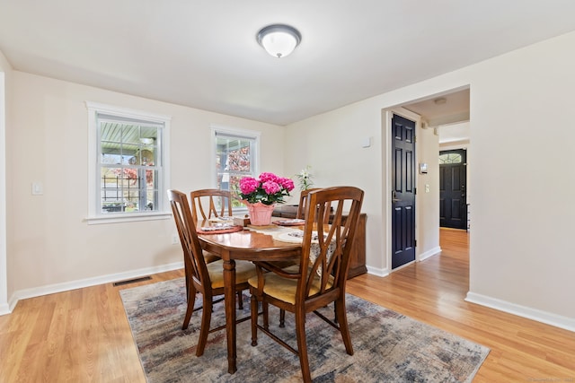 dining room with baseboards, visible vents, and light wood finished floors