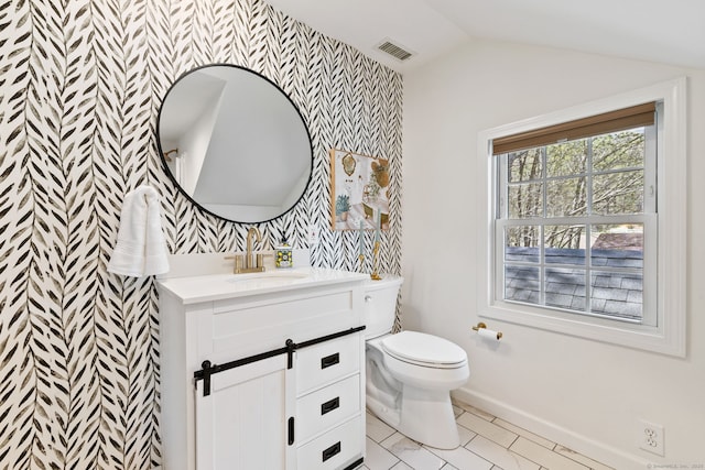 bathroom with vanity, an accent wall, toilet, baseboards, and wallpapered walls