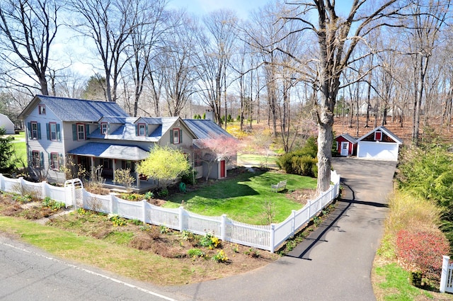 view of front of property featuring a chimney, a fenced front yard, covered porch, driveway, and a front lawn