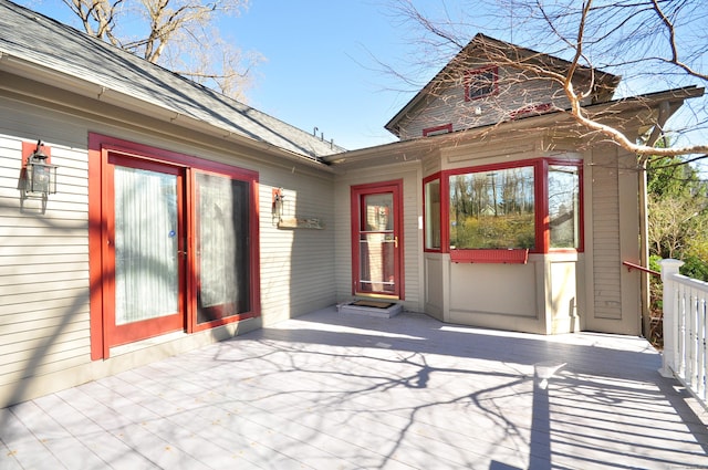 entrance to property with a shingled roof and a wooden deck