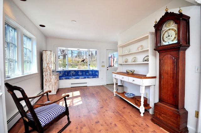 sitting room with wood finished floors, a baseboard heating unit, and baseboards