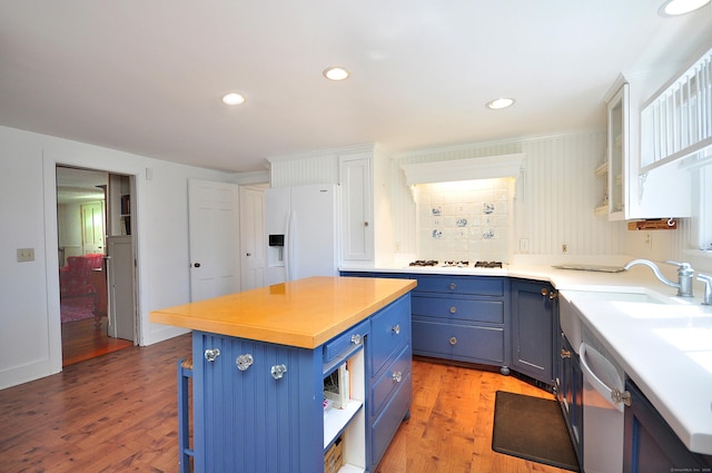 kitchen featuring blue cabinets, white appliances, open shelves, and a sink