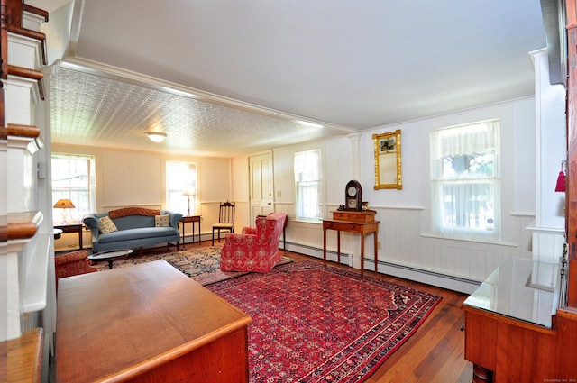 living room featuring baseboard heating, wainscoting, and hardwood / wood-style flooring