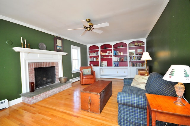 living room with a baseboard heating unit, a brick fireplace, ceiling fan, crown molding, and wood finished floors