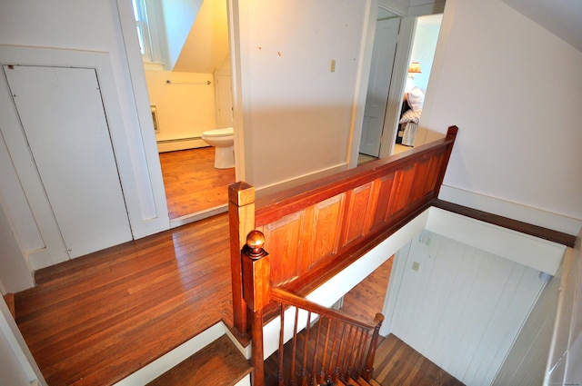 staircase featuring wood finished floors and a baseboard radiator