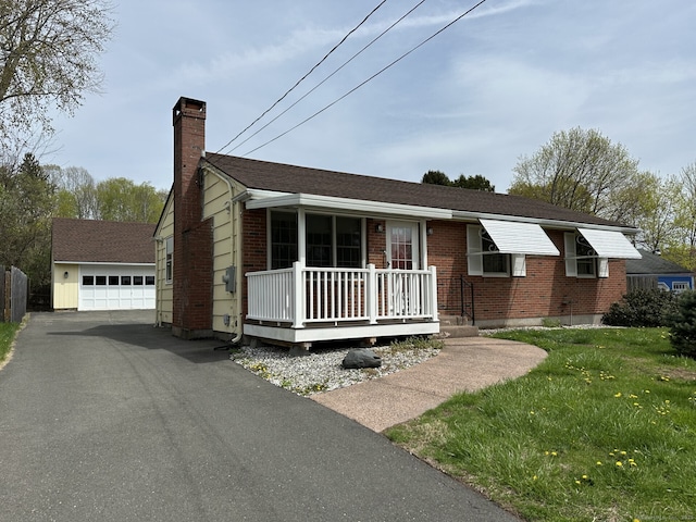 ranch-style home with brick siding, an outbuilding, covered porch, a detached garage, and a chimney