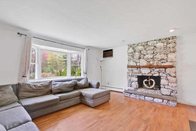 living room featuring crown molding, a stone fireplace, baseboard heating, and wood finished floors