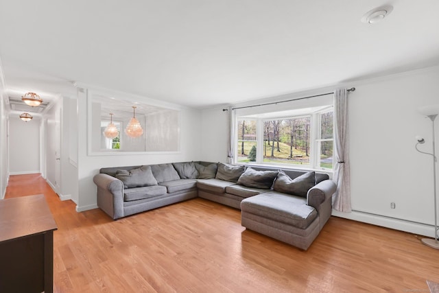 living room with crown molding, baseboard heating, and light wood-type flooring