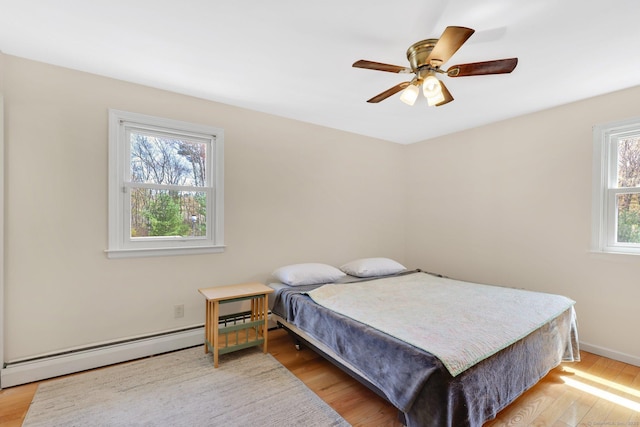 bedroom featuring baseboards, ceiling fan, baseboard heating, and light wood-style flooring