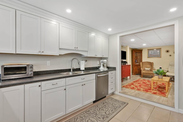 kitchen featuring white cabinets, dark countertops, a sink, dishwasher, and a toaster