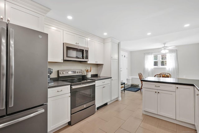 kitchen featuring dark countertops, stainless steel appliances, recessed lighting, white cabinetry, and a ceiling fan