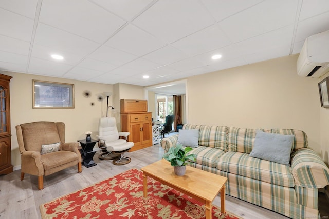 living area featuring light wood-type flooring, recessed lighting, a drop ceiling, and an AC wall unit