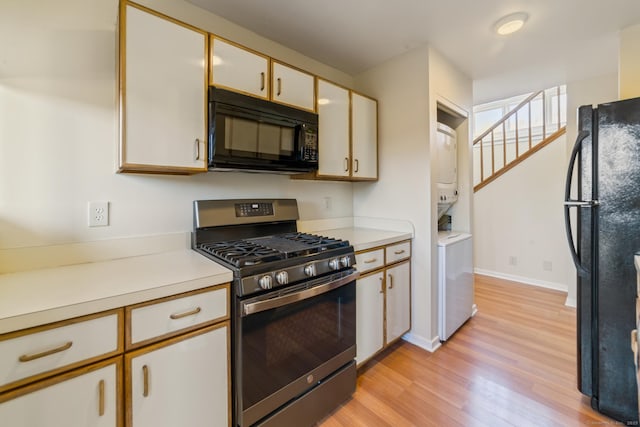 72 Montoya Dr Unit 72, Branford, CT 06405 - kitchen featuring black appliances, stacked washer and clothes dryer, light countertops, and light wood-style floors