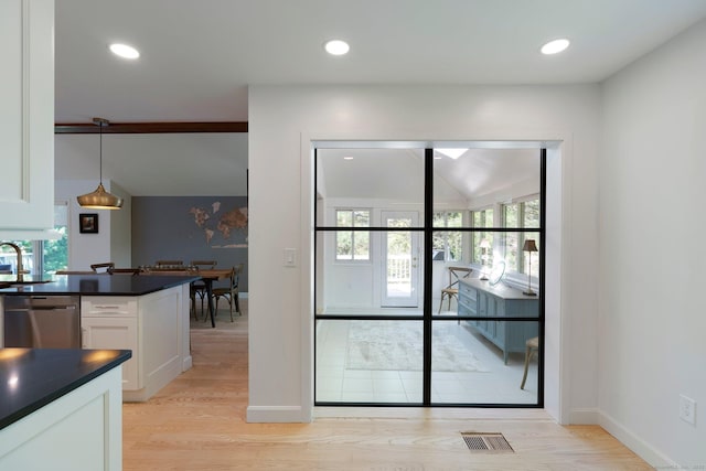 kitchen with dark countertops, stainless steel dishwasher, healthy amount of natural light, white cabinets, and recessed lighting