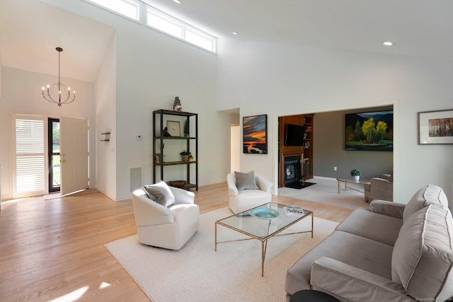 living room featuring high vaulted ceiling, a chandelier, light wood-style flooring, and baseboards