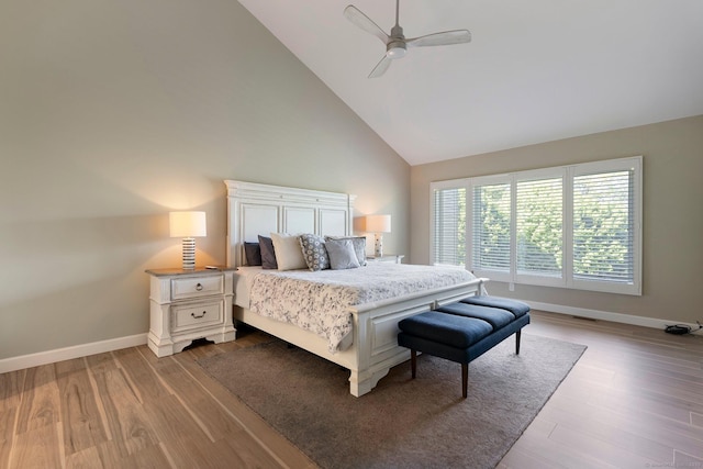 bedroom with high vaulted ceiling, wood finished floors, baseboards, and ceiling fan