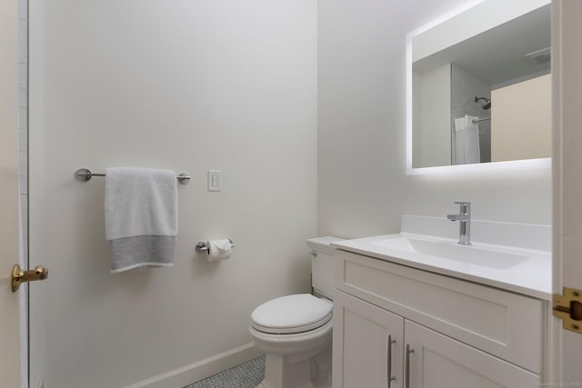 bathroom featuring vanity, toilet, baseboards, and a shower