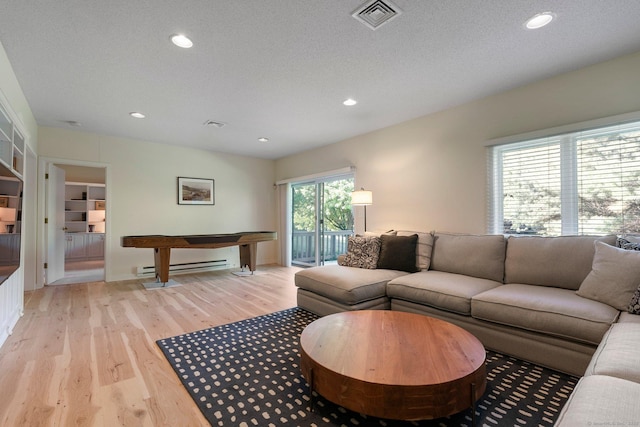 living area featuring light wood-style flooring, baseboard heating, recessed lighting, and a textured ceiling