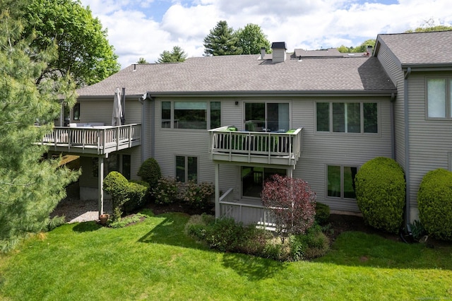 back of property with a chimney, a lawn, and roof with shingles