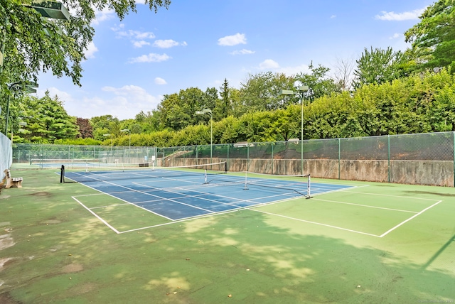 view of tennis court with community basketball court and fence