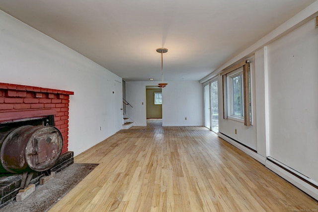 472 Westover Rd, Stamford, CT 06902 - unfurnished living room featuring hardwood / wood-style flooring, a baseboard heating unit, a brick fireplace, and stairs
