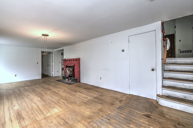 472 Westover Rd, Stamford, CT 06902 - unfurnished living room with a brick fireplace, stairs, and hardwood / wood-style flooring