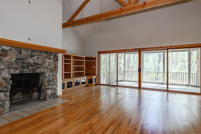 9 Stonehedge Way, Granby, CT 06060 - unfurnished living room featuring a healthy amount of sunlight, high vaulted ceiling, wood-type flooring, and a stone fireplace