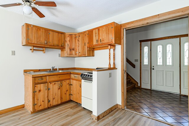 9 Stonehedge Way, Granby, CT 06060 - kitchen with a sink, brown cabinetry, a ceiling fan, baseboards, and white range with gas stovetop