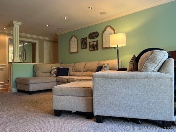 living area featuring ornate columns, recessed lighting, ornamental molding, and carpet