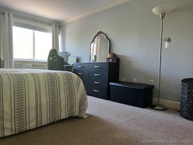 bedroom with crown molding, a wall unit AC, and carpet flooring