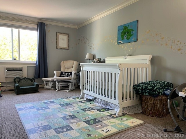 carpeted bedroom featuring ornamental molding, a wall mounted AC, and a nursery area