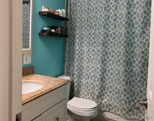 bathroom with toilet, a shower with shower curtain, and vanity