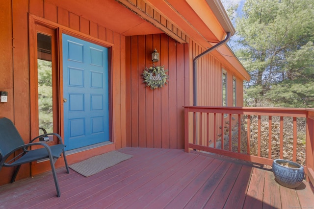 view of exterior entry with board and batten siding and a wooden deck