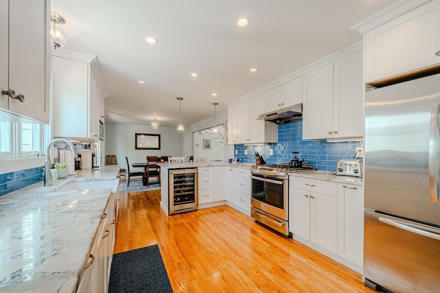 kitchen featuring stainless steel appliances, under cabinet range hood, a sink, white cabinetry, and wine cooler
