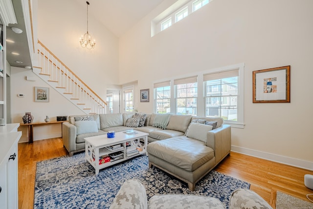 living area featuring stairway, light wood-style floors, high vaulted ceiling, and a notable chandelier