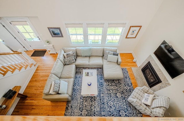 living area with a glass covered fireplace, wood finished floors, and baseboards