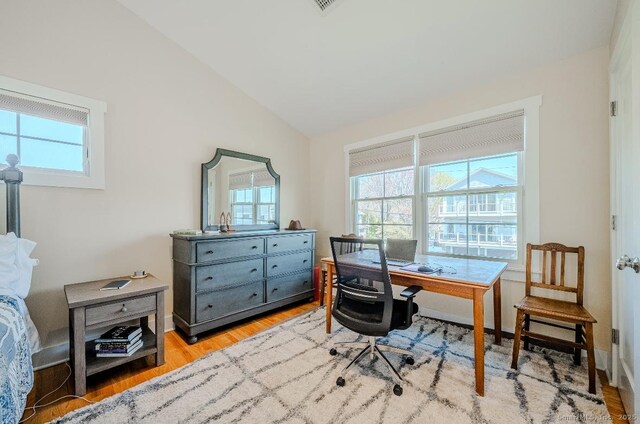 home office featuring a wealth of natural light, light wood-style floors, and lofted ceiling