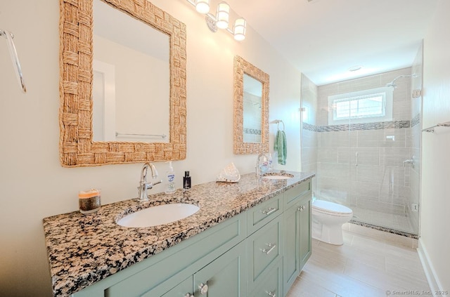 full bath featuring toilet, double vanity, a sink, and a shower stall