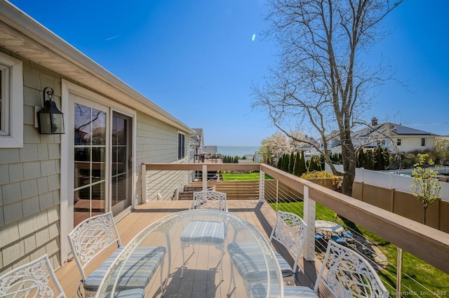 wooden deck with outdoor dining space, a water view, and fence