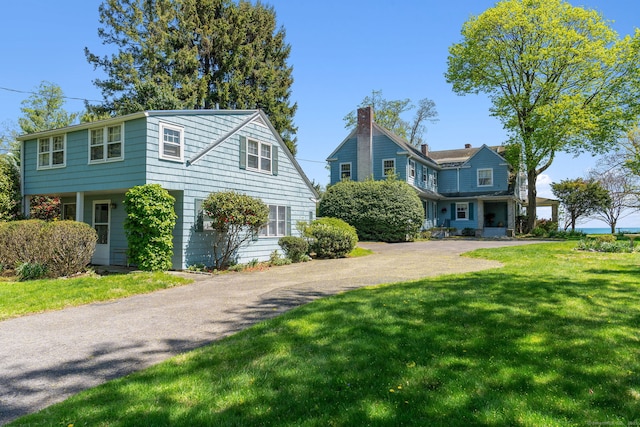 86 Wallacks Dr, Stamford, CT 06902 - view of front of home featuring a front lawn, a chimney, and driveway