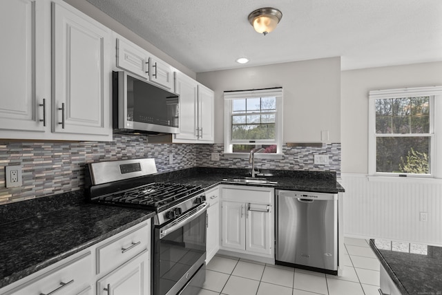 75 Brittania Rd Unit 75, Danbury, CT 06811 - kitchen featuring dark stone counters, white cabinetry, a wainscoted wall, a sink, and stainless steel appliances