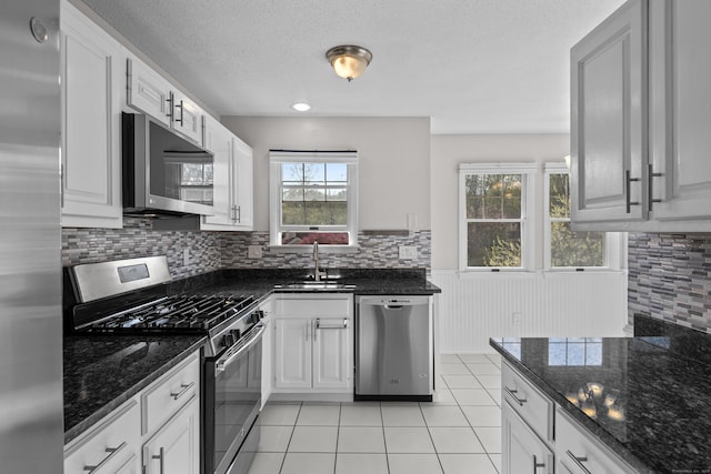 75 Brittania Rd Unit 75, Danbury, CT 06811 - kitchen featuring decorative backsplash, wainscoting, a textured ceiling, a sink, and stainless steel appliances