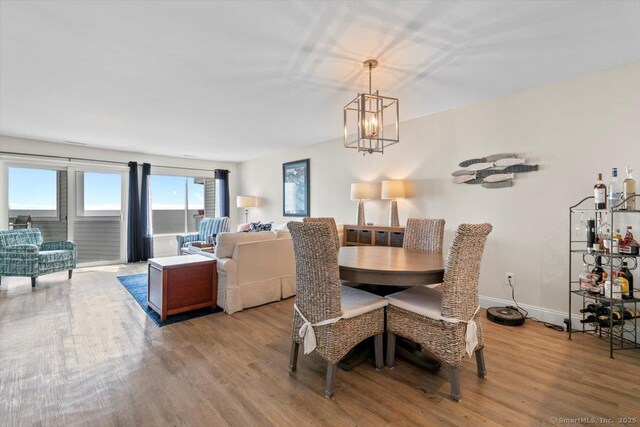 dining area with light wood-style floors and an inviting chandelier