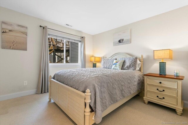 bedroom with baseboards, light colored carpet, and visible vents