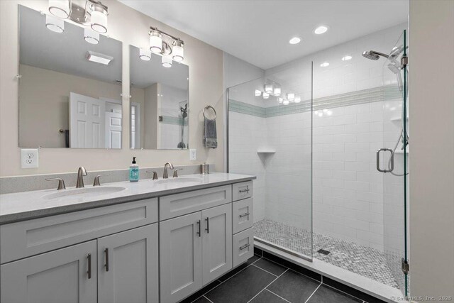 bathroom with a sink, tile patterned flooring, a shower stall, and double vanity