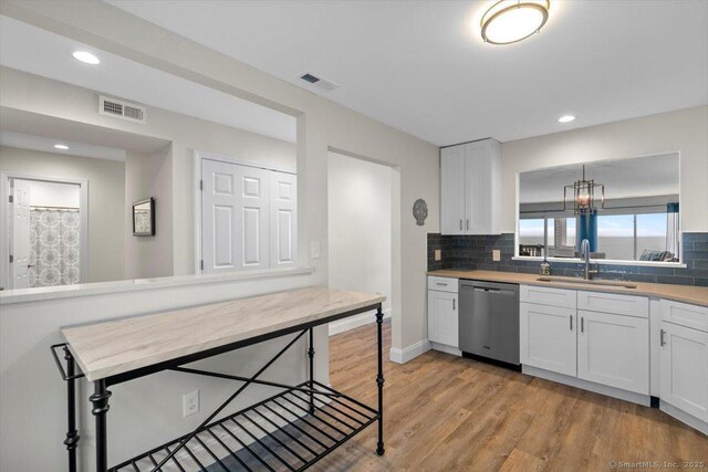 kitchen with a sink, light countertops, backsplash, stainless steel dishwasher, and visible vents