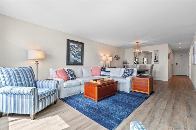living area with recessed lighting, baseboards, a notable chandelier, and light wood-type flooring
