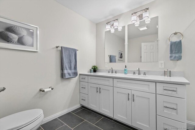 bathroom featuring a sink, tile patterned flooring, toilet, and double vanity