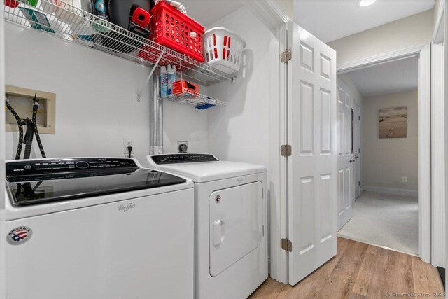clothes washing area with light wood-style floors, baseboards, laundry area, and washing machine and dryer