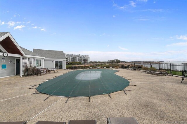community pool with a patio area and fence